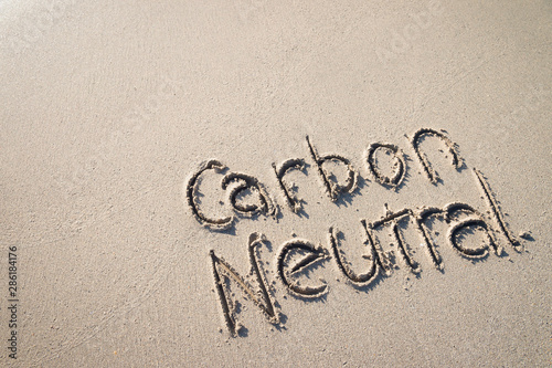 Carbon Neutral message handwritten on smooth sand beach 