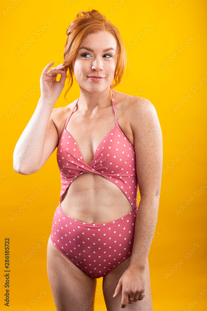 Cute girl with red hair and freckles wearing a pink polka dot