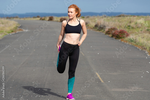 Pretty woman with red hair exercising outside