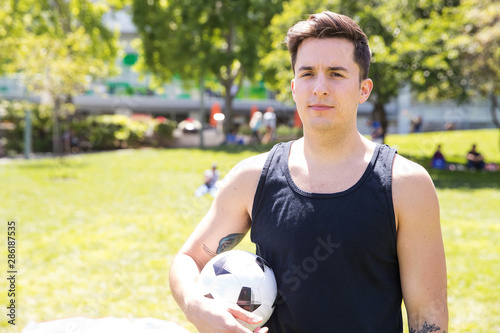 handsome man holding a soccer ball in a park