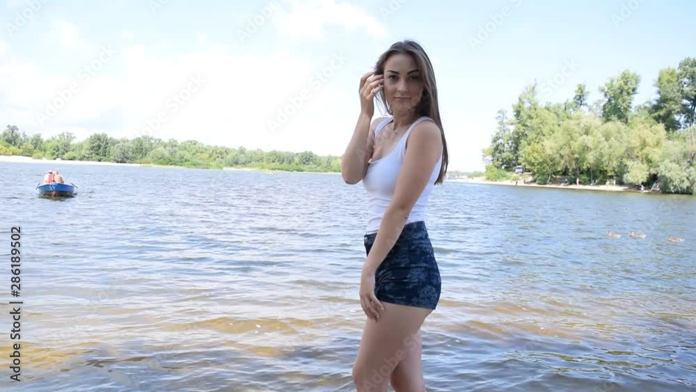 A young girl stands near the river in nature.