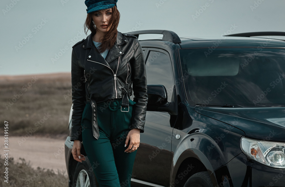 High fashion portrait of brunette woman outside in leather black jacket and trendy hat. Outdoor fashion.