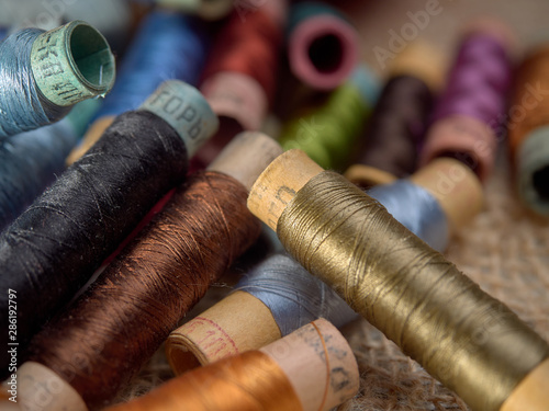 Bright thread on wooden spools, thimbles and needles