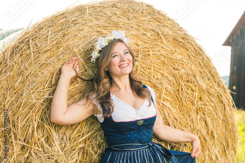 Frau in Tracht vor einem Strohballen an einem sonnigem Tag in bayern photo