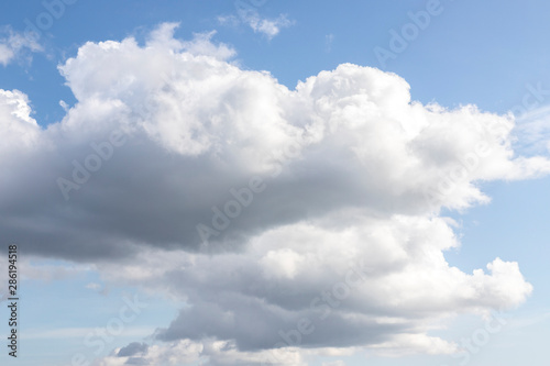 Blue sky with white clouds. Big dark cloud on the blue sky. Cloudy daytime weather. Background with free space and empty place.