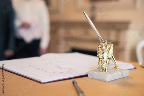 Closeup at the wedding ceremony. Eagle emblem on a pen holder and documents to sign