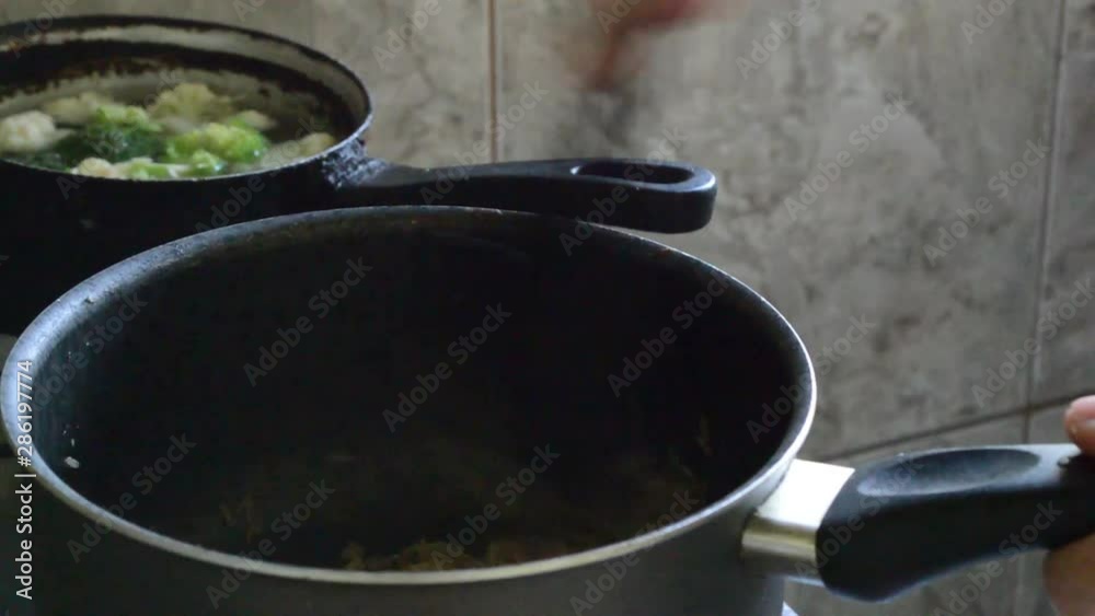 female hand braising brown rice in pan on stove female hand braising brown rice in pan on stove