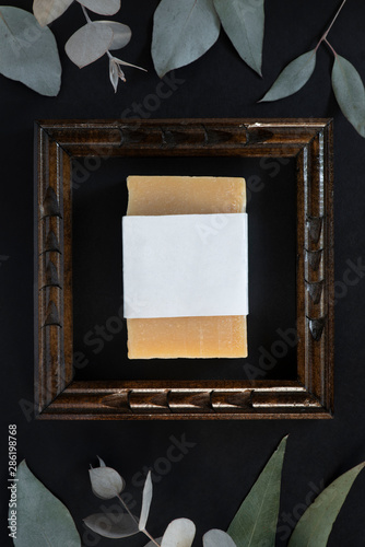 orange natural bar soap made with mahogany essential oil in small wooden frame with surrounded by green leaves  handmade soap  handmade soap with blank label  mockup label flat lay