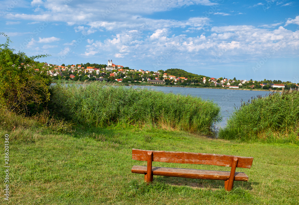 Tihany village and the abbey at lake Balaton from the inner lake with a wooden bench in the foreground in Hungary Tihany village and the abbey at lake Balaton from the inner lake with a wooden bench in the foreground in Hungary
