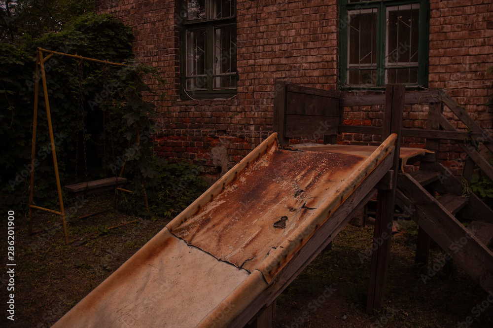 Old wooden swings in a yard with brick wall Old wooden swings in a yard with brick wall