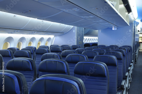 Empty commercial airplane cabin interior with blue leather seats on a widebody commercial aircraft. 