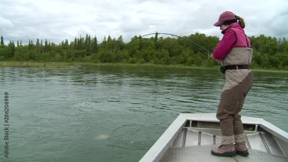 female fly angler fighting hooked King salmon from boat female fly angler fighting hooked King salmon from boat