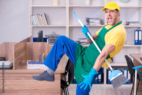 Young male contractor cleaning the office © Elnur