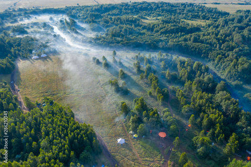 Obraz na płótnie Fog floats over the forest and a field and a star-shaped tent w salonie