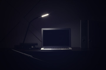 Modern workplace with laptop in evening