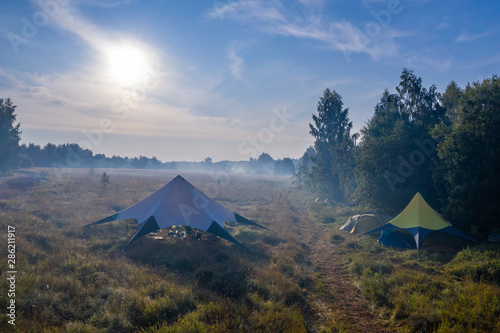 Morning fog evaporates from the field on which stands a star-shaped tent