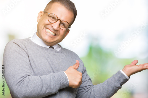 Middle age bussines arab man wearing glasses over isolated background Showing palm hand and doing ok gesture with thumbs up  smiling happy and cheerful