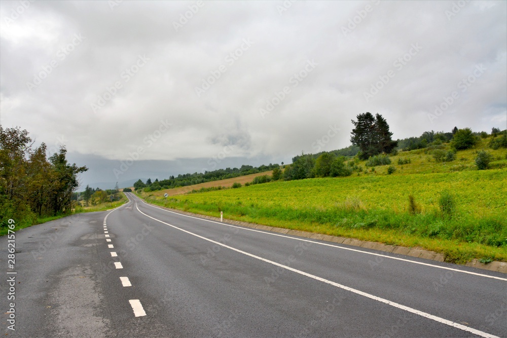 Fototapeta premium a road on field with cloudy sky