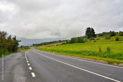 a road on field with cloudy sky
