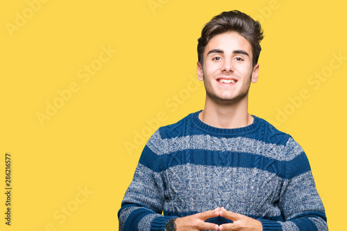 Young handsome man over isolated background Hands together and fingers crossed smiling relaxed and cheerful. Success and optimistic