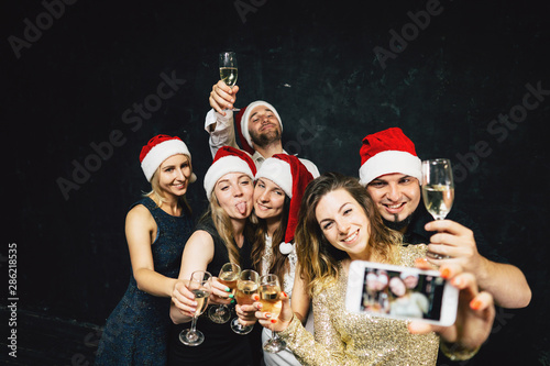 Christmas celebration, friendship, winter holidays. Happy people drinking champagne taking selfie on New Year party.