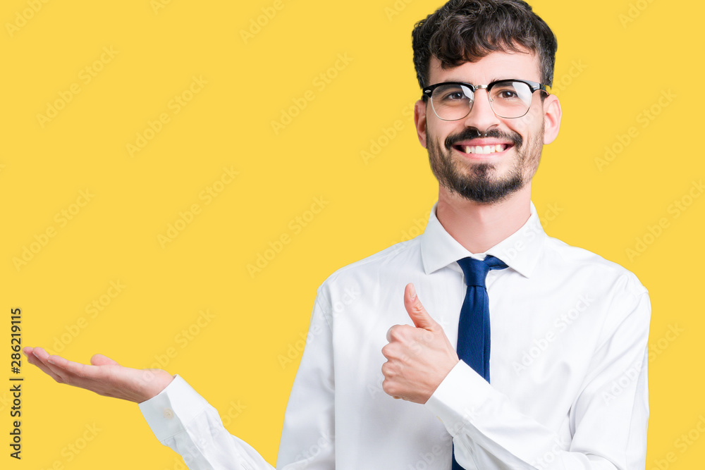 Young handsome business man wearing glasses over isolated background Showing palm hand and doing ok gesture with thumbs up, smiling happy and cheerful