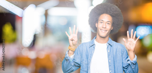 Young african american man with afro hair showing and pointing up with fingers number nine while smiling confident and happy.