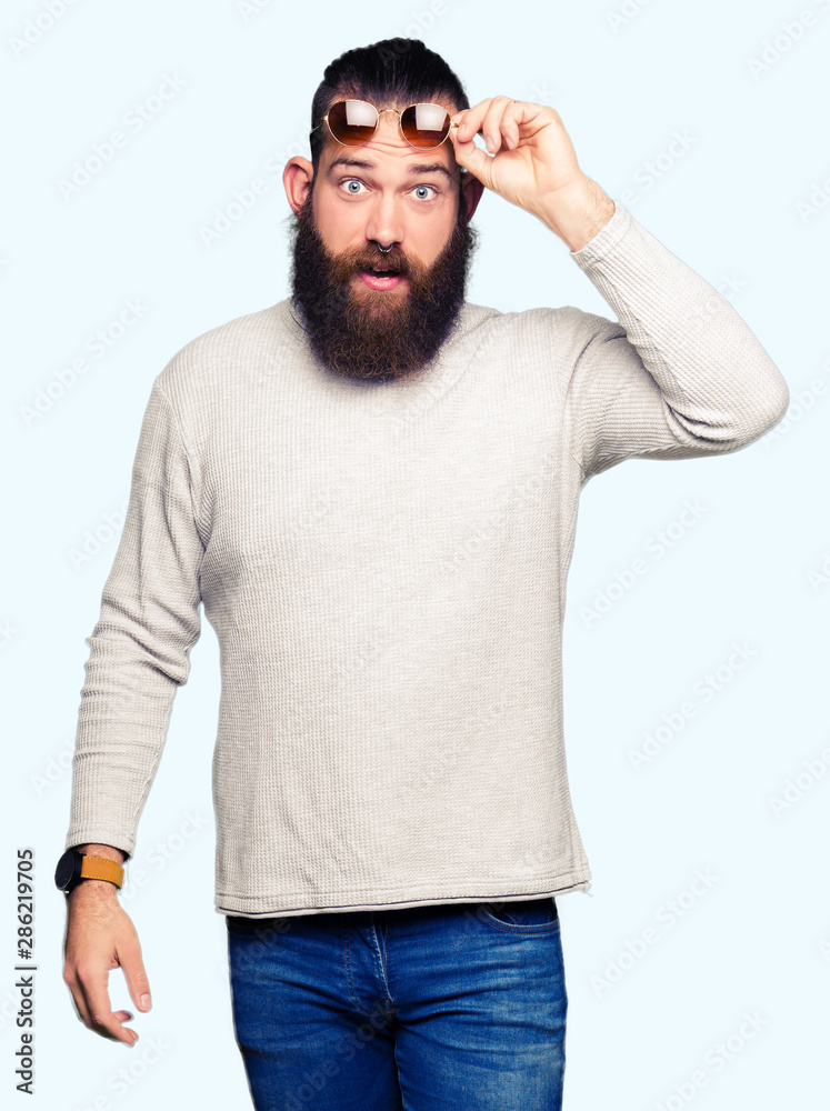 Young hipster man wearing sunglasses afraid and shocked with surprise expression, fear and excited face. Young hipster man wearing sunglasses afraid and shocked with surprise expression, fear and excited face.