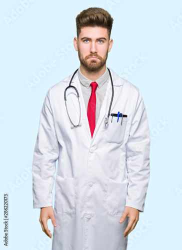 Young handsome doctor man wearing medical coat depressed and worry for distress, crying angry and afraid. Sad expression.