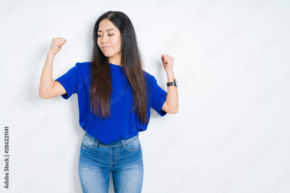 Beautiful brunette woman over isolated background showing arms muscles smiling proud. Fitness concept.
