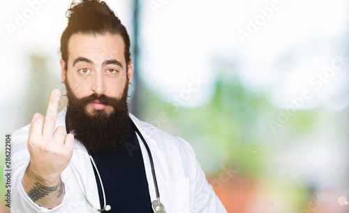 Doctor with long hair wearing medical coat and stethoscope Showing middle finger, impolite and rude fuck off expression