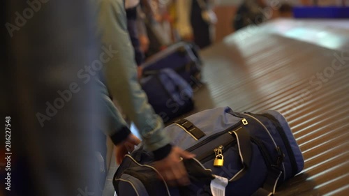 People are claiming their baggages on conveyor belt and a man taking his luggage