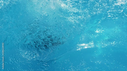 active young woman jumps into the clear blue water of the pool on resort in the hotel in Slow motion