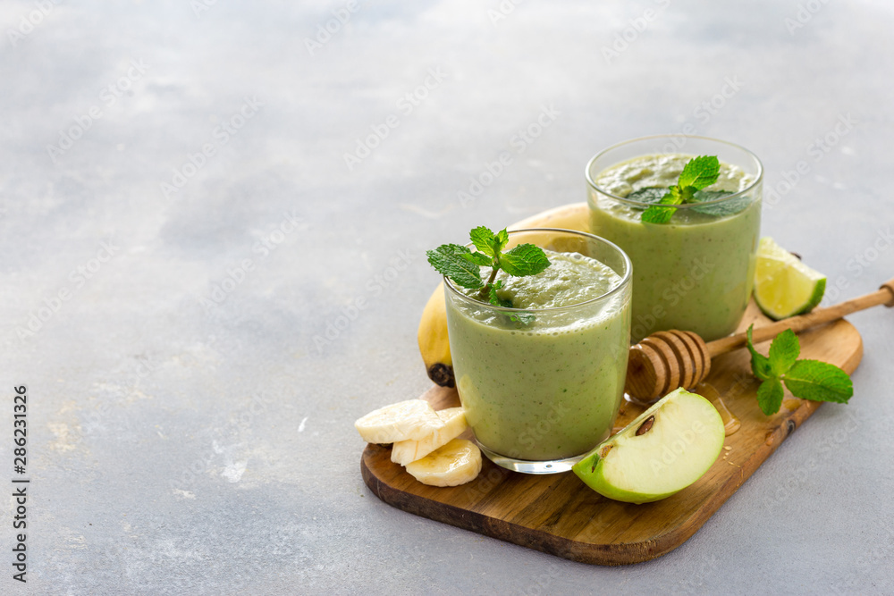Glass mug with green health smoothie of apple banana lime and honey on a table with copy space Glass mug with green health smoothie of apple banana lime and honey on a table with copy space