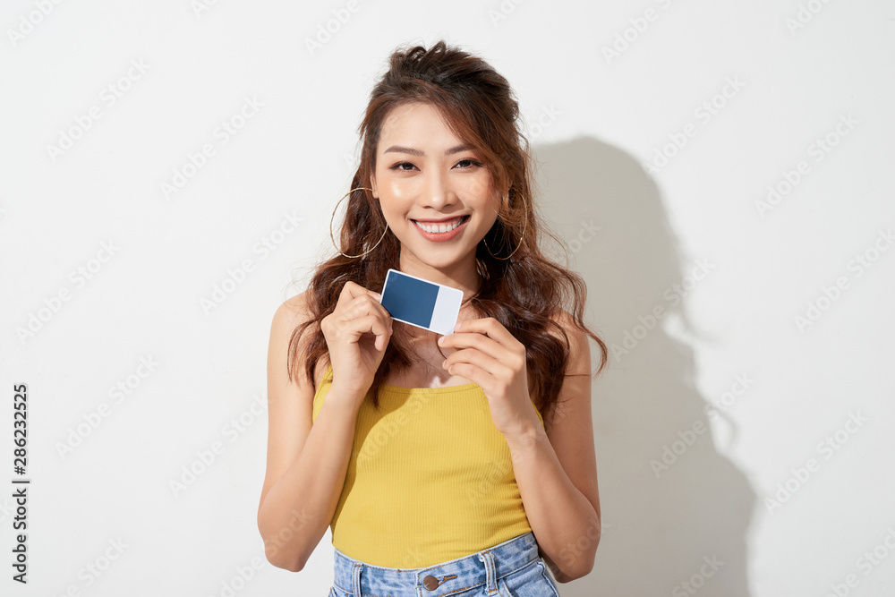 Portrait of an excited happy asian woman holding credit card isolated over white background Portrait of an excited happy asian woman holding credit card isolated over white background