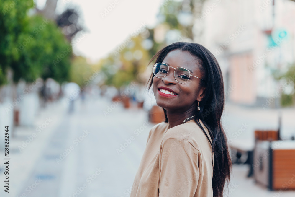 Young cool black skin girl with glasses walking in the street. Young cool black skin girl with glasses walking in the street.