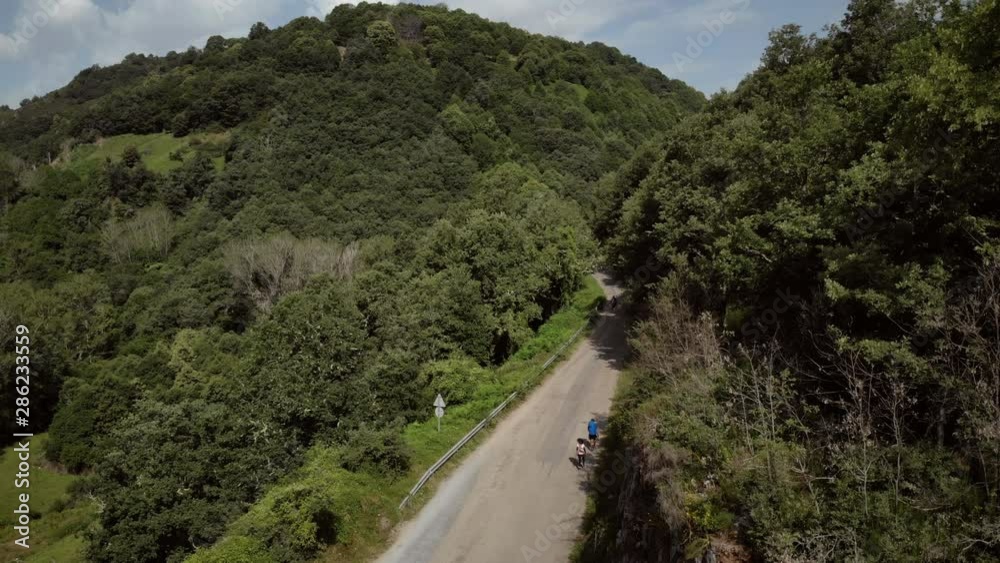 Aerial view of pilgrims walking on path near Villafranca del Bierzo, Spanish town along Camino de Santiago or Way of St. James. People on road in Spain seen from drone flying in sky Aerial view of pilgrims walking on path near Villafranca del Bierzo, Spanish town along Camino de Santiago or Way of St. James. People on road in Spain seen from drone flying in sky