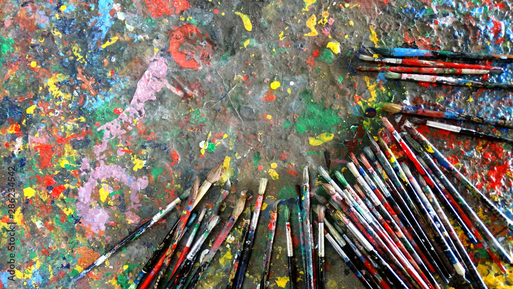 Fototapeta premium Used paint brushes on a table with pigments stained, arts and handworks concept image.