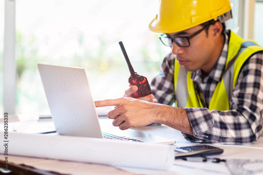 Architect working on blueprint.engineer inspective in workplace - architectural project, blueprints,ruler,calculator,laptop and divider compass.