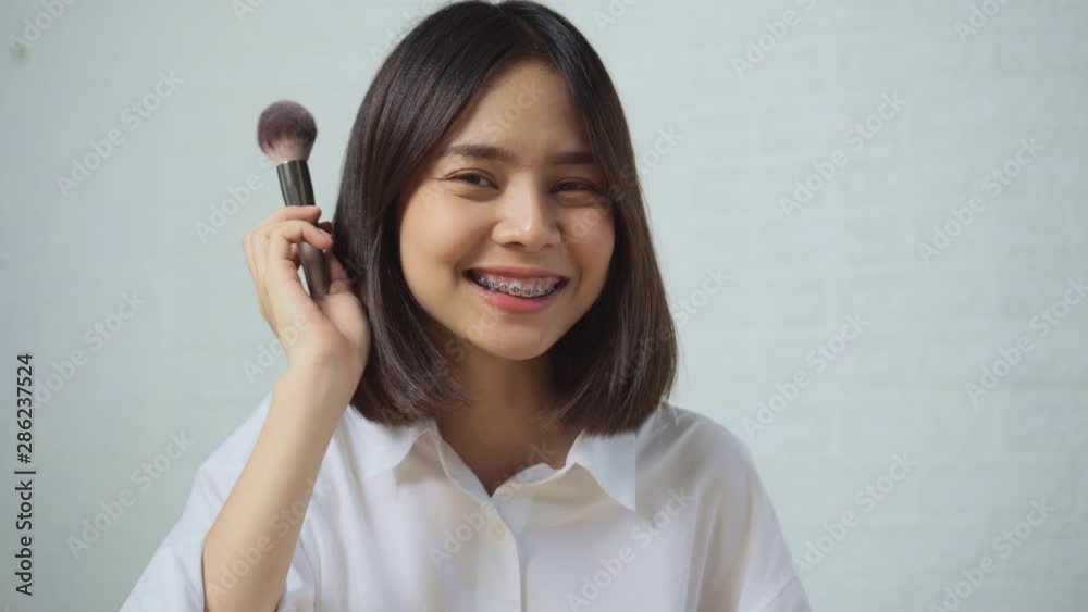 Young Asian woman applies makeup on the face. Young Asian woman applies makeup on the face.
