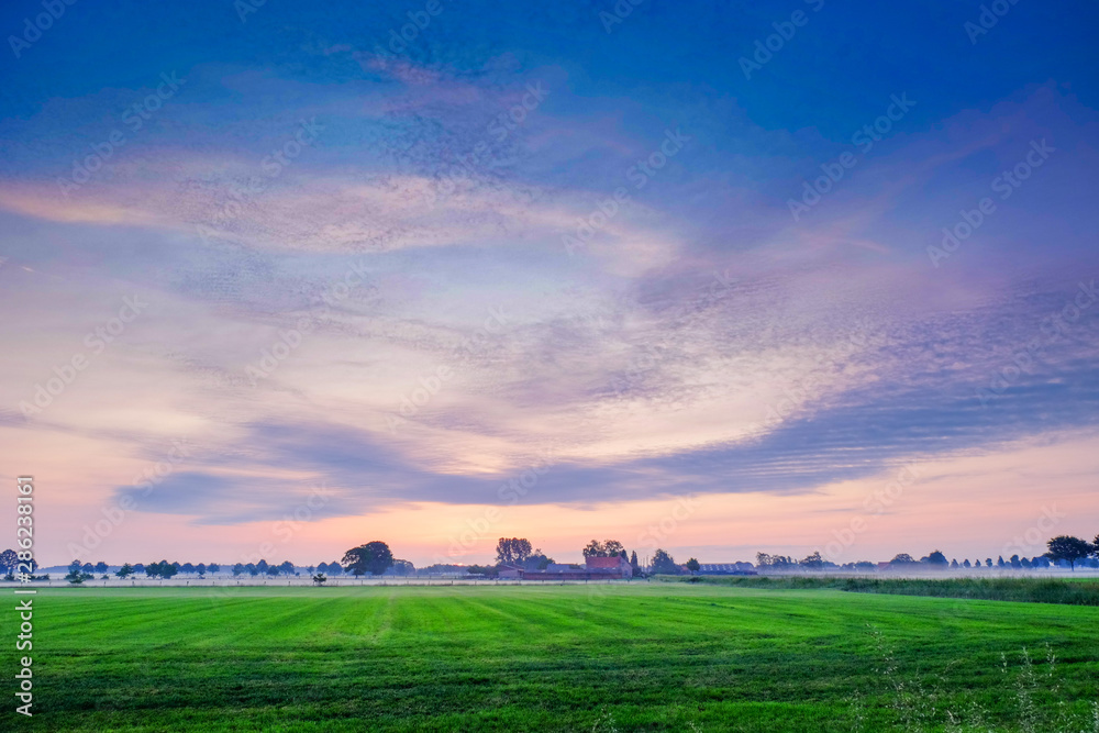 Colorful glowing sunrise over a countryside farming area, creating an idyllic scenic landscape