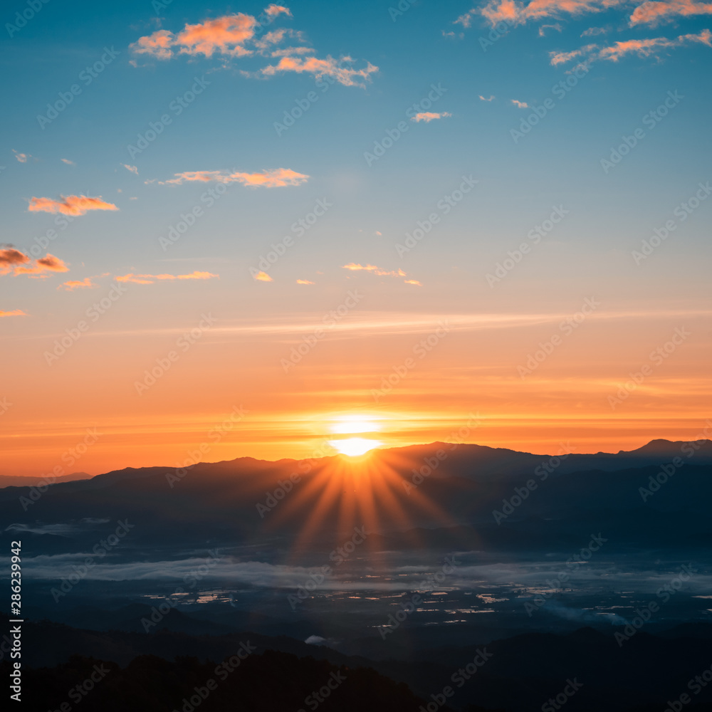 Beautiful foggy winter sunrise in mountains background.