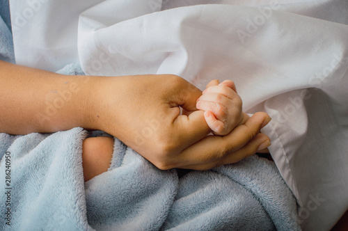 Suaves manos de bebé. Bebé recién nacido mano en la palma de su madre. La mano del niño en la mano de una madre sobre una manta. Nuevo concepto de familia, cuidado y protección del bebé. Piel escamosa