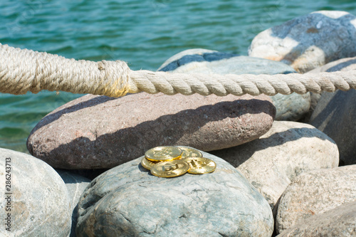 Bitcoin on sea stones, in background sea. Concept freelance, stock exchange.Background with copy space for text