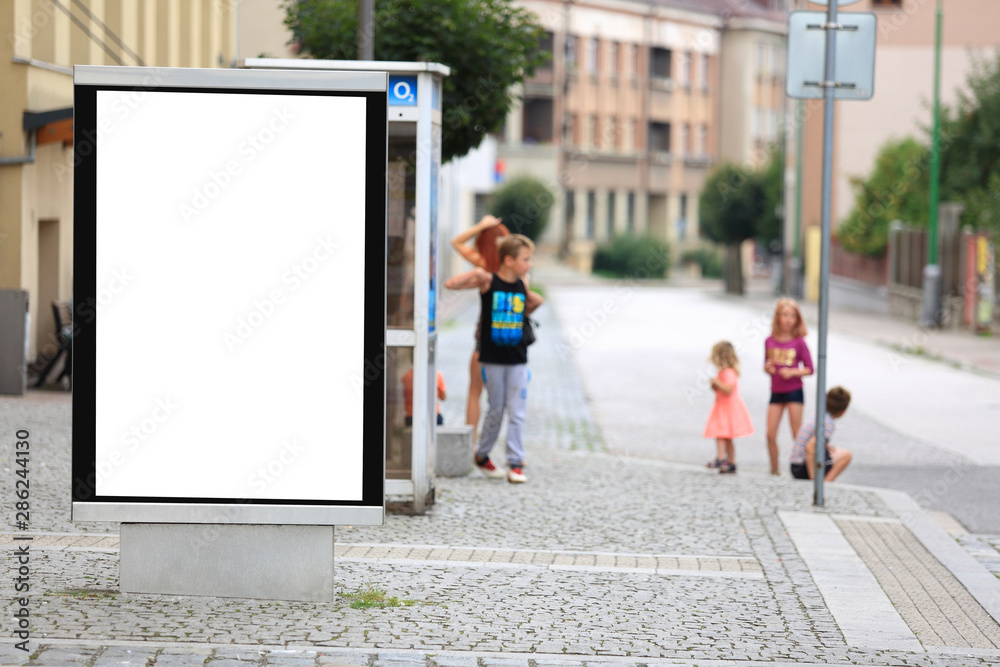 Bilbord reklamowy w centrum miasta, w tle dzieci na chodniku, przystanku autobusowym.  - obrazy, fototapety, plakaty 
