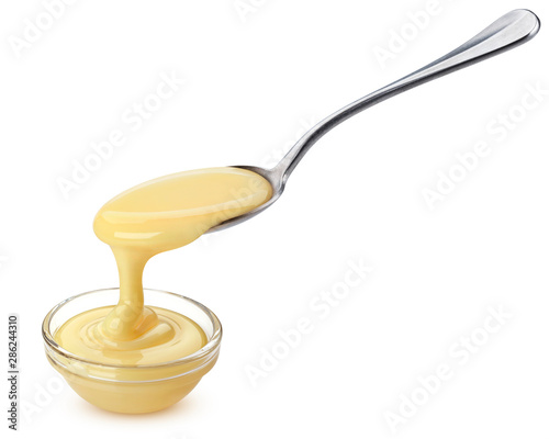 Foto Pouring condensed milk isolated on white background
