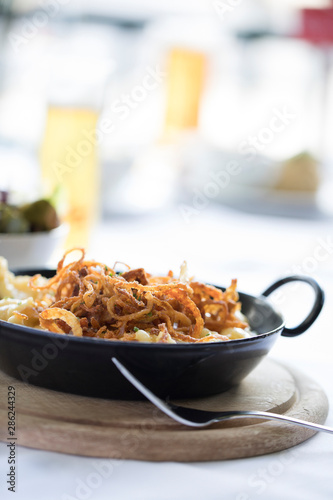 traditional alpine cheese dish in a iron pan served on a wooden board photo