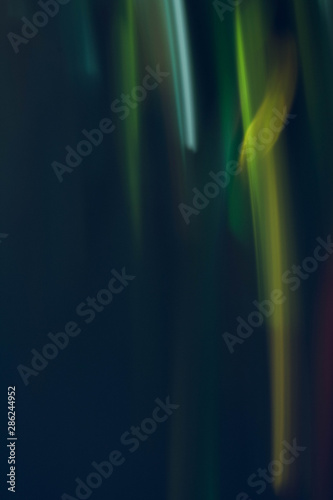 Defocused lights leak. Blur green and yellow glowing lines. Dark abstract background.