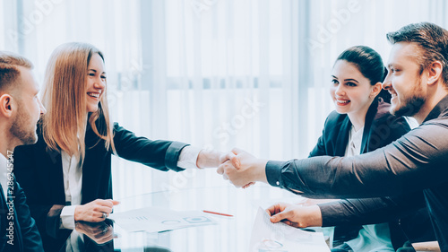 Professional cooperation. Business partners closing deal, shaking hands in modern conference room. photo