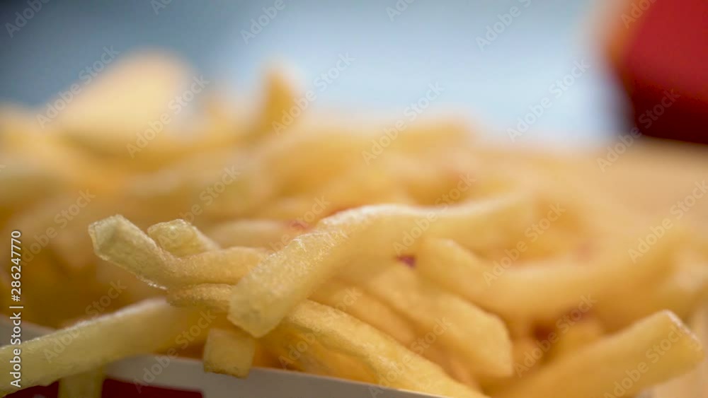 slow motion close-up static shot of ketchup drops poured onto a box of French fries slow motion close-up static shot of ketchup drops poured onto a box of French fries